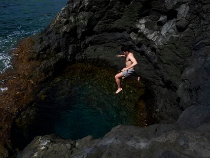 Un hombre salta al agua desde los acantilados junto a la playa de Echentive, al sur de la isla de La Palma (Canarias).