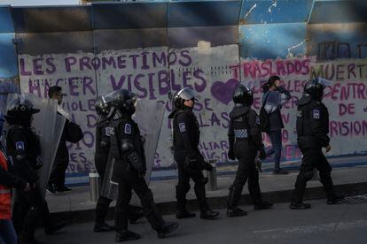 Elementos de la Secretaría de Seguridad Ciudadana caminan frente a vallas metálicas que han sido pintadas.