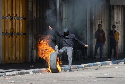 Un palestino lanza contra soldados israelíes un neumático ardiendo en la ciudad cisjordana de Hebrón, tras la muerte de Jader Adnan, este martes.