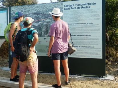 Tres visitantes leen indicaciones de los carteles que llevan a Sant Pere de Rodes.