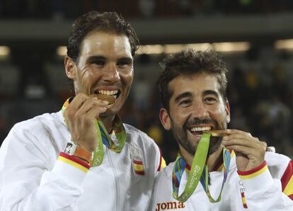 Los tenistas españoles Rafael Nadal y Marc mordiendo el oro logrado en tenis de dobles masculino.