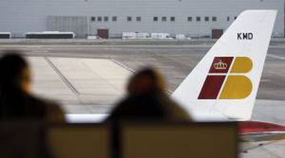 Dos personas ante un avión de Iberia, en el aeropuerto Adolfo Suárez - Barajas. EFE/Archivo