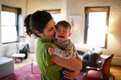 Una madre coge con cariño a su bebé llorando.