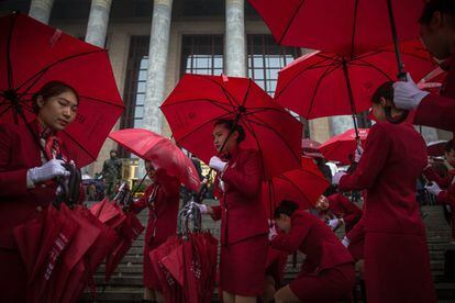 Azafatas se protegen de la lluvia con paraguas antes del comienzo de la inauguración del XIX Congreso Nacional del Partido Comunista en Pekín (China), 18 de octubre de 2017.