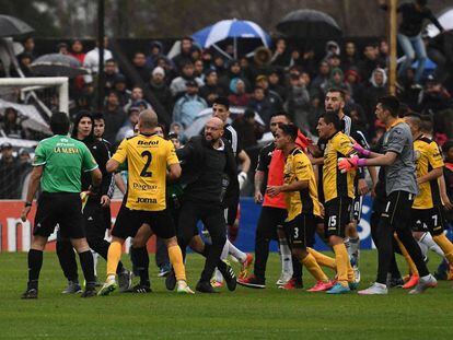 Los jugadores de Comunicaciones increpan a Freire, encapuchado.