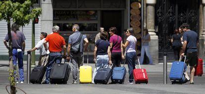 Un grupo de turistas tira de sus maletas en un paso de peatones de la Gran V&iacute;a de Madrid.