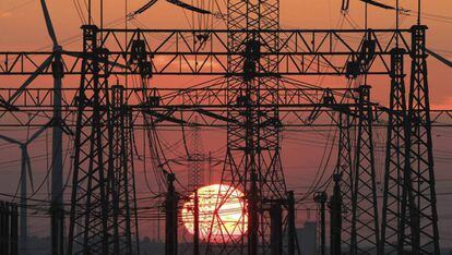 A la imatge, una posta de sol amb l'estesa elèctrica i uns molins de vent.