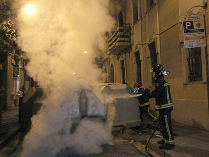 Los bomberos apagan un contenedor encendido en la manifestaci&oacute;n del jueves pasado en Gr&agrave;cia.