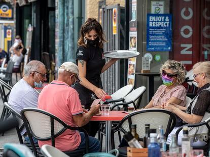 Una camarera sirve a unos clientes en una terraza en Benidorm.