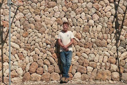Lluc Mir frente a un muro de piedra seca levantado por él en Mallorca.