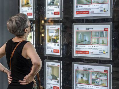 Una mujer revisa los carteles de una inmobiliaria en Barcelona.