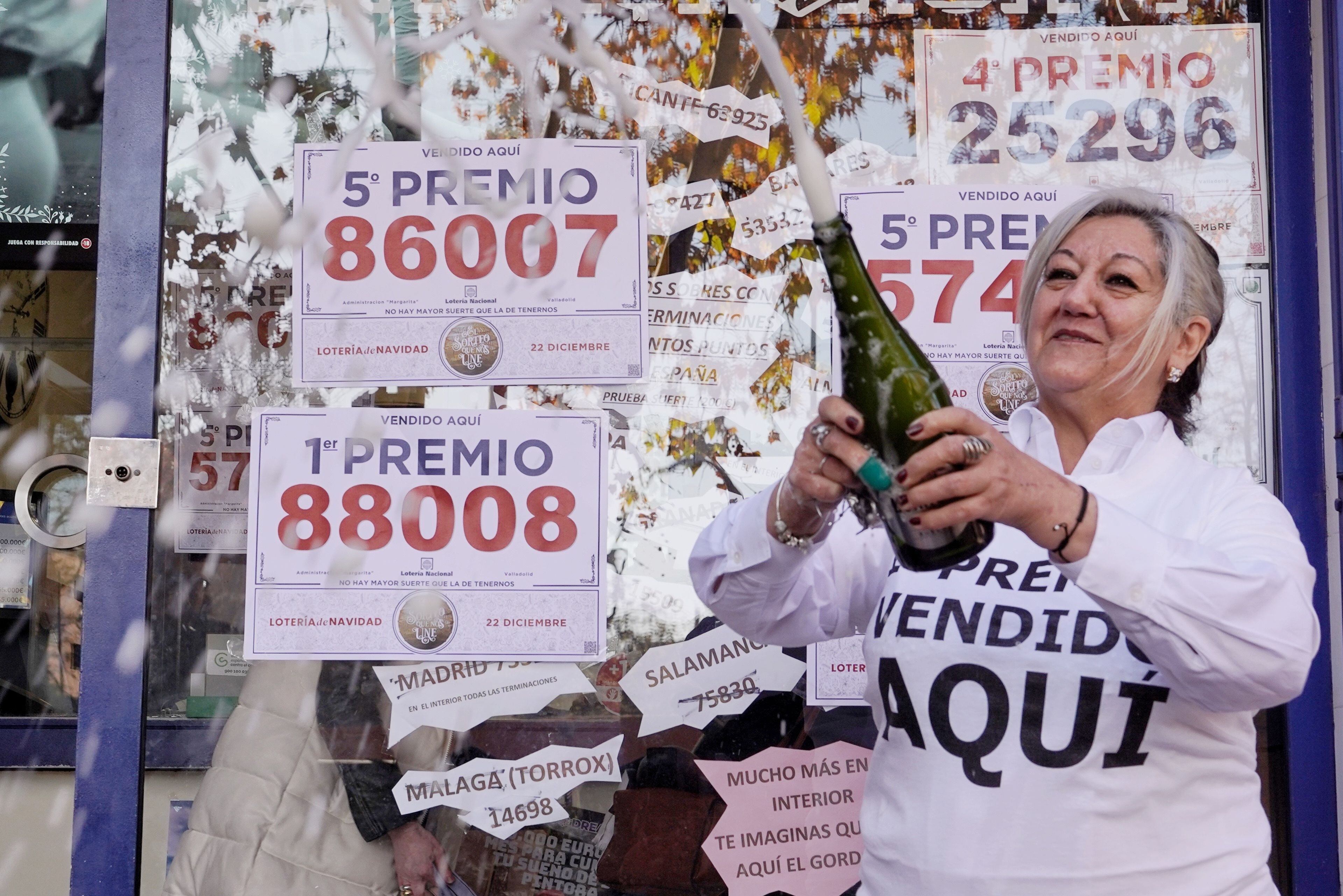 Belén Cima, propietaria de la administración número 14 de Valladolid celebra la venta de dos quintos premios y del primer premio del sorteo de lotería de Navidad en su establecimiento.
