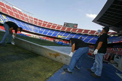 Unos operarios retocan el césped del Camp Nou tras un concierto de Bruce Springsteen.