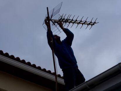 Un hombre revisa la antena de una vivienda. 