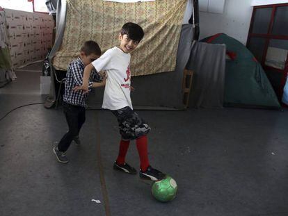 Dos ni&ntilde;os juegan en el campamento de refugiados del antiguo estadio de hockey Olympic Complex, en Atenas.