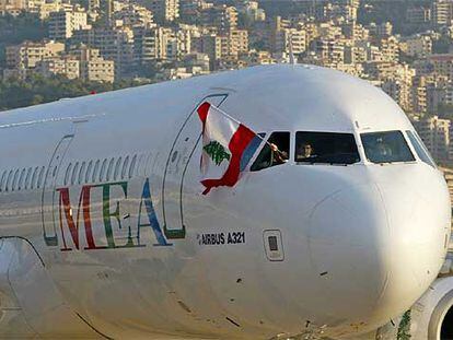 Un tripulante de un avión de la compañía Middle East Airlines ondea una bandera libanesa tras aterrizar en el aeropuerto de Beirut.