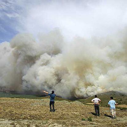 Unos jóvenes miran impotentes cómo el fuego calcina los alredededores de Santa María del Espino.