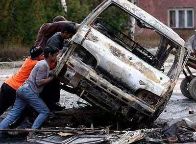 Unos hombres vuelcan un vehículo de la ONU quemado en Mitrovica, ocupada ayer por tropas de la OTAN.
