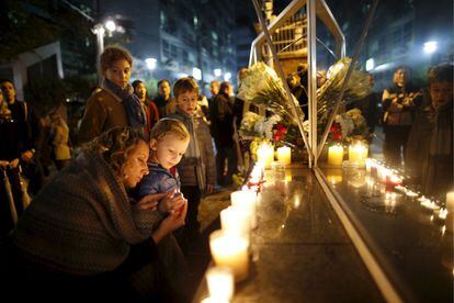 Una madre enciende una vela junto a su hijo cerca de la embajada de Francia en Seúl (Corea del Sur) durante un homenaje a las víctimas de los atentados de París, el 14 de noviembre de 2015.