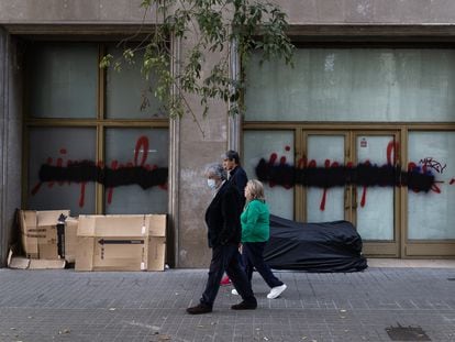 Varios viandantes pasan ante un portal donde duermen personas sin hogar, en Barcelona el pasado octubre.
