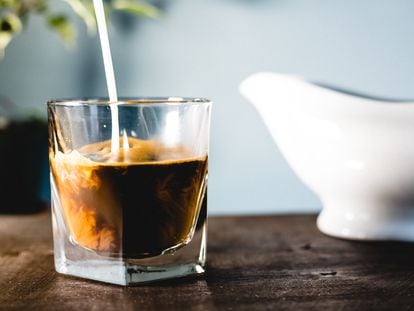 Pouring milk and coffee in a glass with a blue background