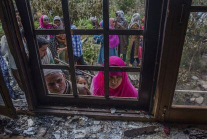 Ciudadanos de Cachemira observan el interior de una casa dañada tras un enfrentamiento entre los militares indios y los rebeldes en la localidad de Kakpora (India).