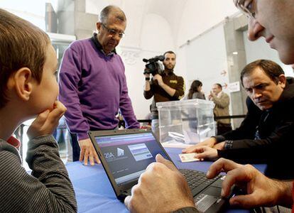 Los miembros de una de las mesas comprueban los datos de un votante en un colegio instalado en la Casa de la Cultura de Girona.