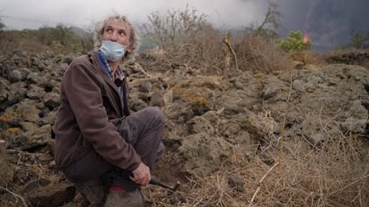 El vulcanólogo Vicente Soler (IPNA-CSIC) pica el terreno para instalar un sismógrafo en La Palma, con el volcán al fondo.