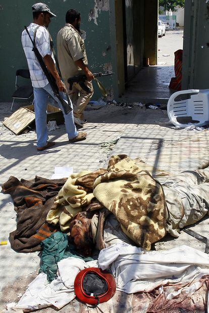 Dos rebeldes pasan junto a unos cadáveres en Bab el Azizia.