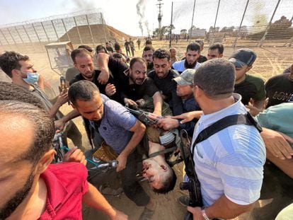Un grupo de palestinos trasladan el cuerpo de un joven israelí asesinado en la frontera sur entre Israel y Gaza, este sábado. 