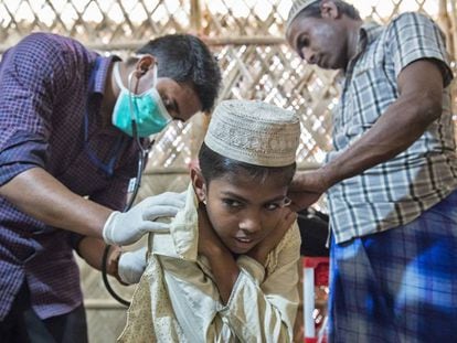 Un médico de MSF inspecciona la espalda de un niño con varicela en presencia de su padre.