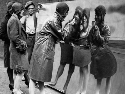 Unas chicas londinenses se miran en un espejo distorsionado. Fotograf&iacute;a de 1930.