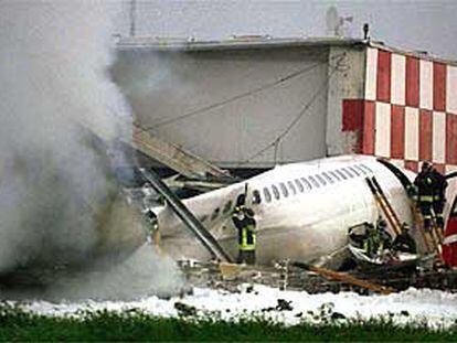 Bomberos italianos examinan los restos del avión de la SAS tras el choque en el aeropuerto de Linate, Milán.