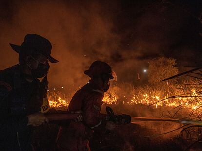 Police officer and a firefighter spray waters in effort to extinguish wildfires in Ogan Ilir regency, South Sumatra province, Indonesia, September 20, 2023, in this photo taken by Antara Foto. Antara Foto/Nova Wahyudi/ via REUTERS  ATTENTION EDITORS - THIS IMAGE HAS BEEN SUPPLIED BY A THIRD PARTY. MANDATORY CREDIT. INDONESIA OUT. NO COMMERCIAL OR EDITORIAL SALES IN INDONESIA.