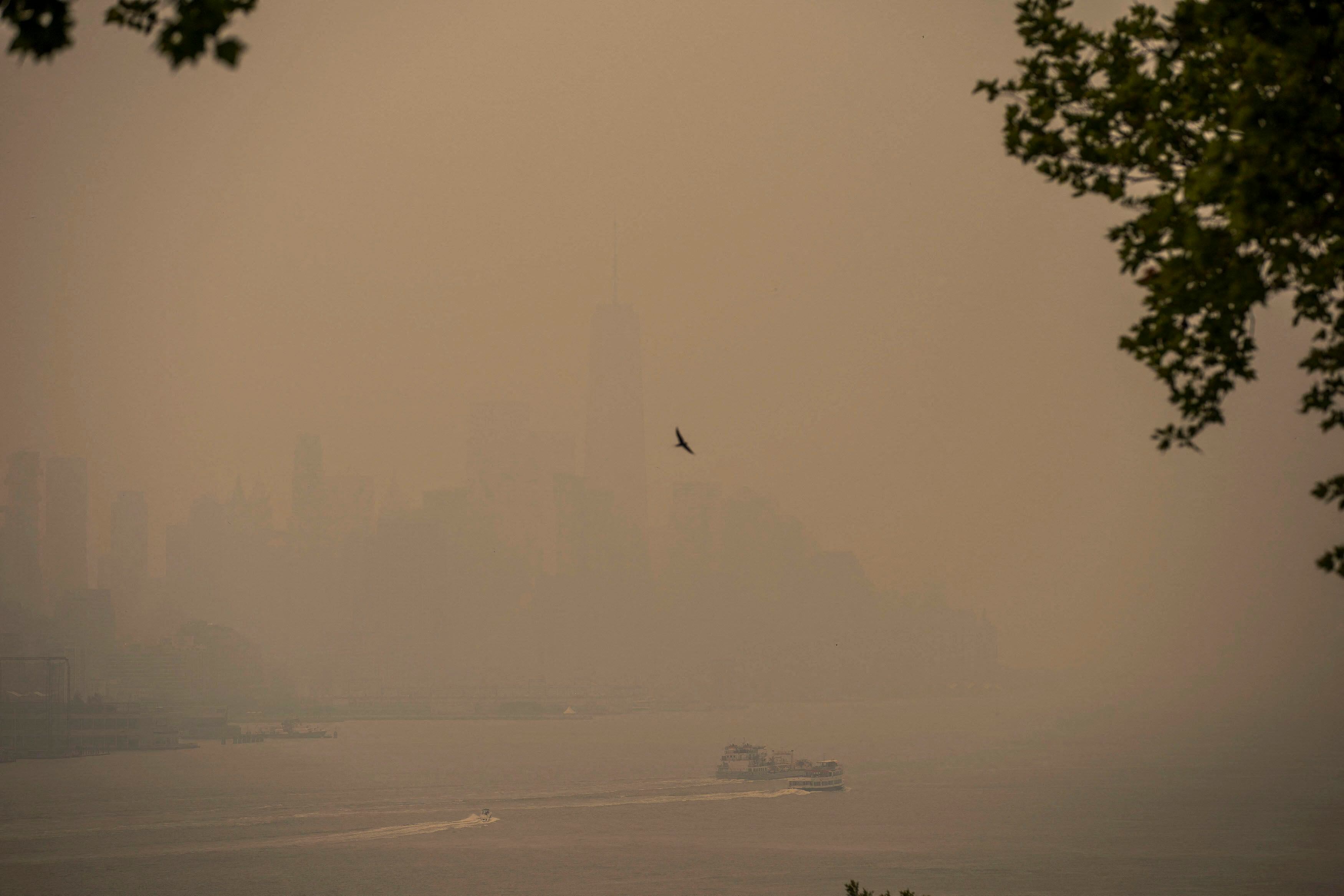 Un barco navega por el río Hudson mientras el horizonte de la ciudad de Nueva York está nublado, debido a los incendios forestales de Canadá, este miércoles. La contaminación por el humo ha empezado a provocar retrasos y cancelaciones de algunos vuelos, aunque el tráfico aéreo no se ha visto gravemente afectado de momento.