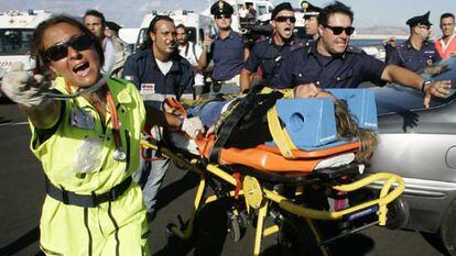 Personal sanitario italiano se abre paso para trasladar al hospital a uno de los pasajeros rescatados.