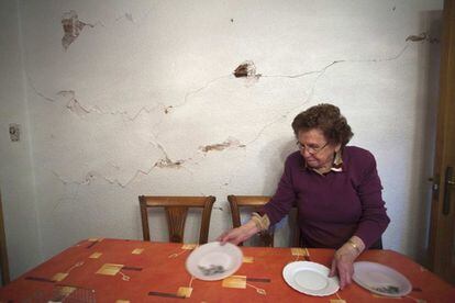 Francisca García pone la mesa en su comedor de su casa de Lorca. La grietas causadas por el terremoto siguen en las paredes.