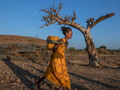 Una mujer de Tigray que huyó del conflicto en esta región de Etiopía, lleva agua a la espalda en un campamento de refugiados en Sudán.