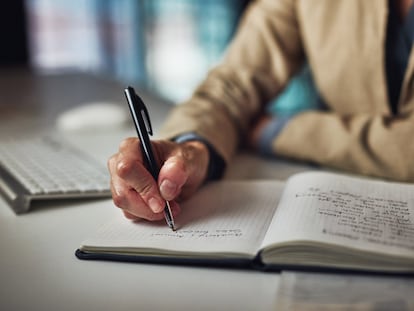 Un hombre toma notas en un cuaderno.