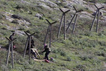 Un grupo de sirios pasan por debajo de una valla alambrada para entrar en territorio turco cerca de Reyhanli, ayer.