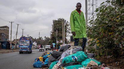 Evans Otieno posa encima de plásticos y basura en descomposición en el asentamiento chabolista de Dandora, Nairobi.