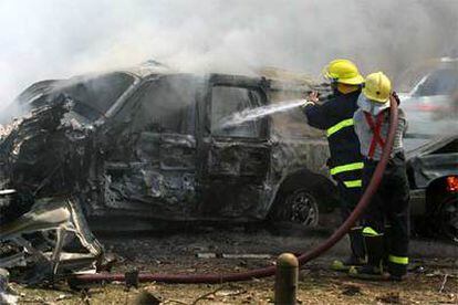 En la imagen, bomberos iraquíes extinguen el fuego en uno de los vehículos afectados.
