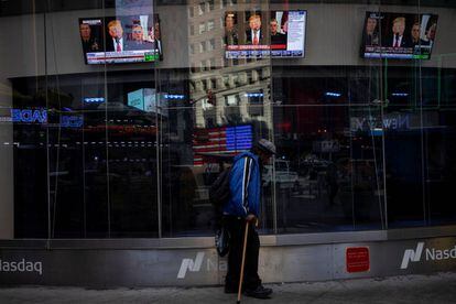 Un hombre pasa por delante de un escaparate con imágenes de un discurso del presidente de EE UU, Donald Trump, en Nueva York. 