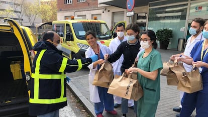 Un trabajador voluntario de Correos entrega comida a varios sanitarios de Madrid.