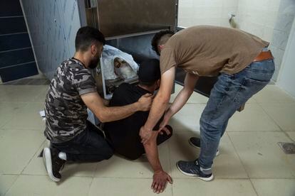 Dos familiares del palestino Mohammad al-Shami, de 23 años, miran su cuerpo en la morgue del hospital en la ciudad cisjordana de Jenin, el lunes 3 de julio de 2023. Shami murió durante una redada militar israelí en el campo de refugiados de Jenin.