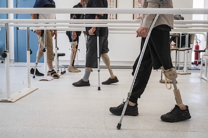 En la sala de rehabilitación de hombres, un grupo de sobrevivientes a la explosión de minas terrestres realizan ejercicios de movilidad con las prótesis para pies y piernas.