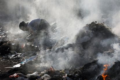 Un hombre busca material reciclable de un montón de desechos informáticos profanados y humeantes en Karachi, Pakistán.
