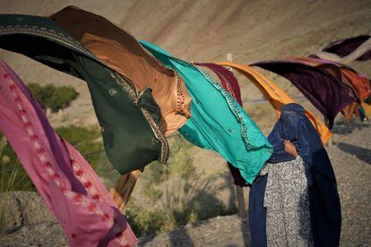 Una mujer elige telas para comprar en un tenderete en la carretera que lleva de Jalalabad a Kabul