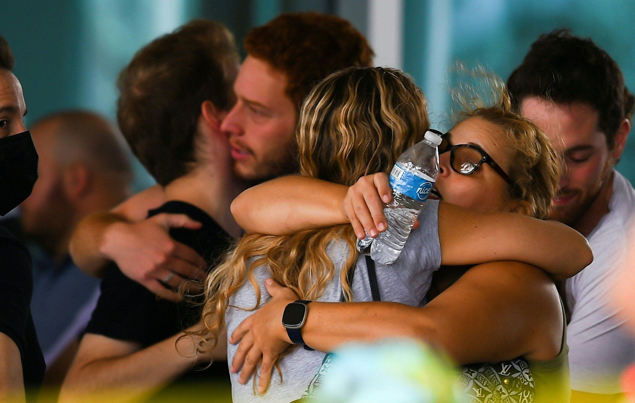 Varias personas se abrazan mientras esperan a recibir noticias de sus familiares tras el colapso del edificio en Surfside.