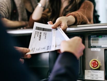 Un pasajero recogiendo dos tarjetas de embarque en el mostrador de facturación de un aeropuerto.
